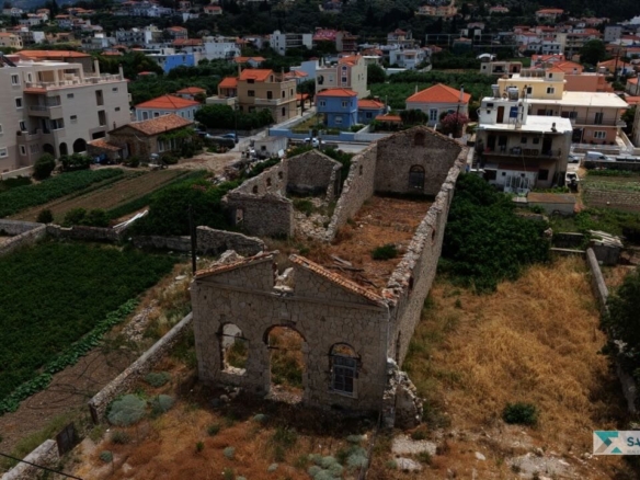 Aerial view of the SH589 plot's ruined stone building among the houses of Karlovasi, Samos
