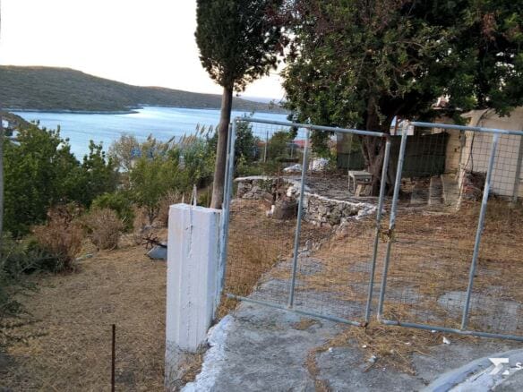 Plot gate with a glimpse of the sea through the trees